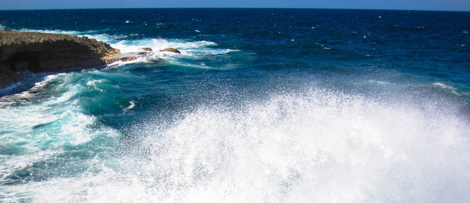 there is a wave crashing against a rocky shore