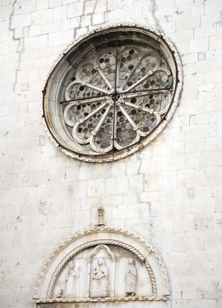 a white building has a large window with a decorative design