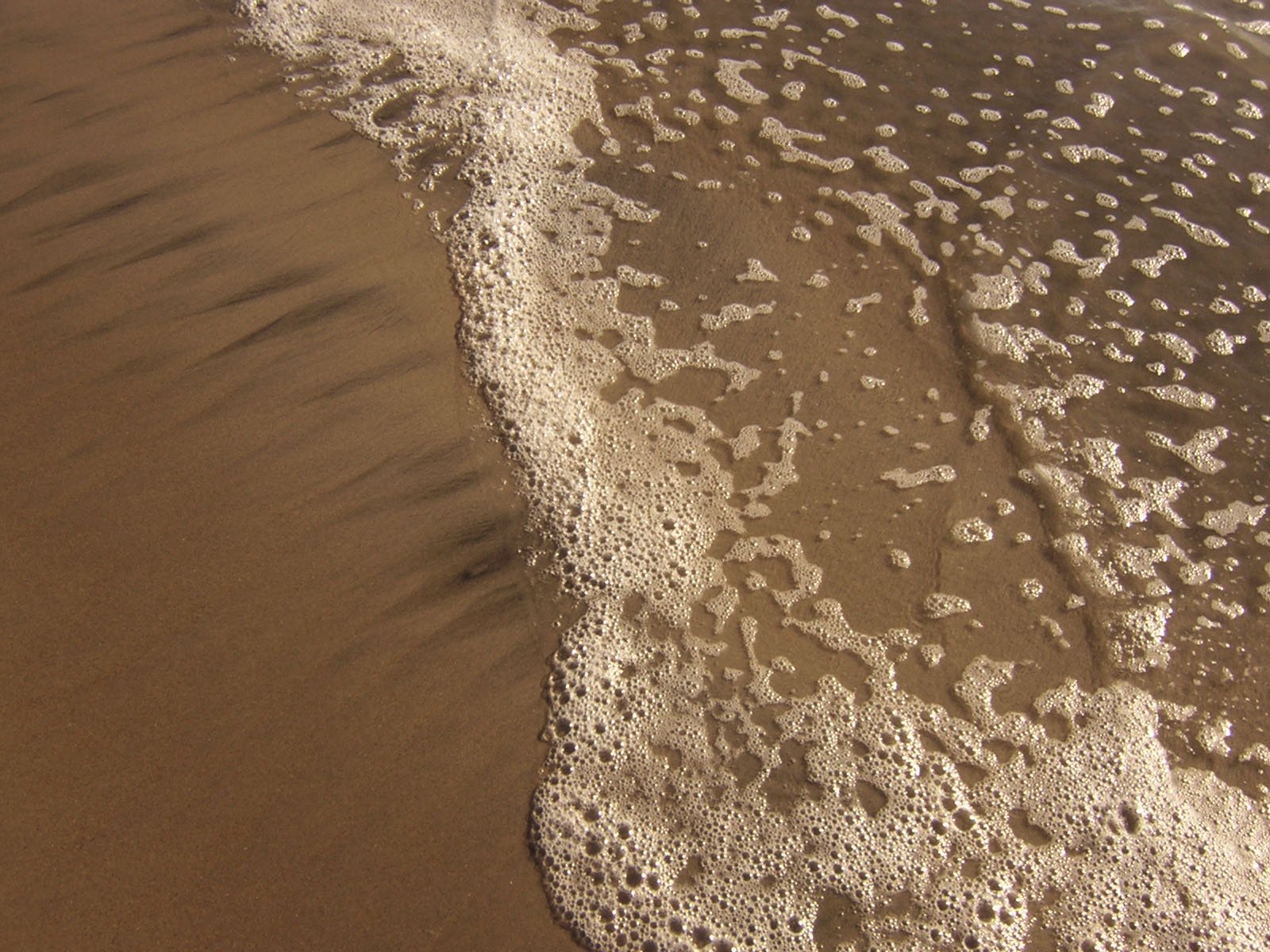 small waves coming in and out from a sandy beach