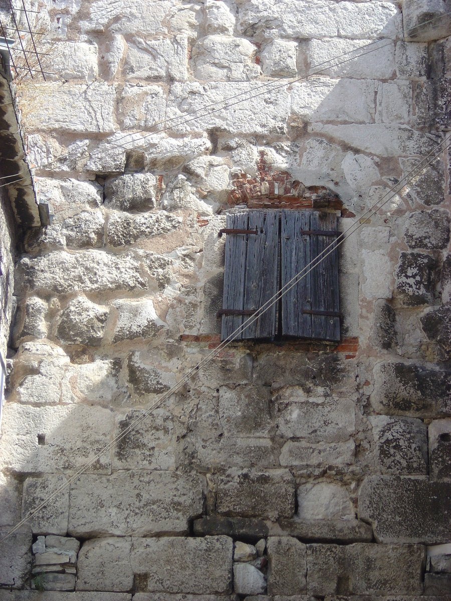 a stone building with two shutters in the outside