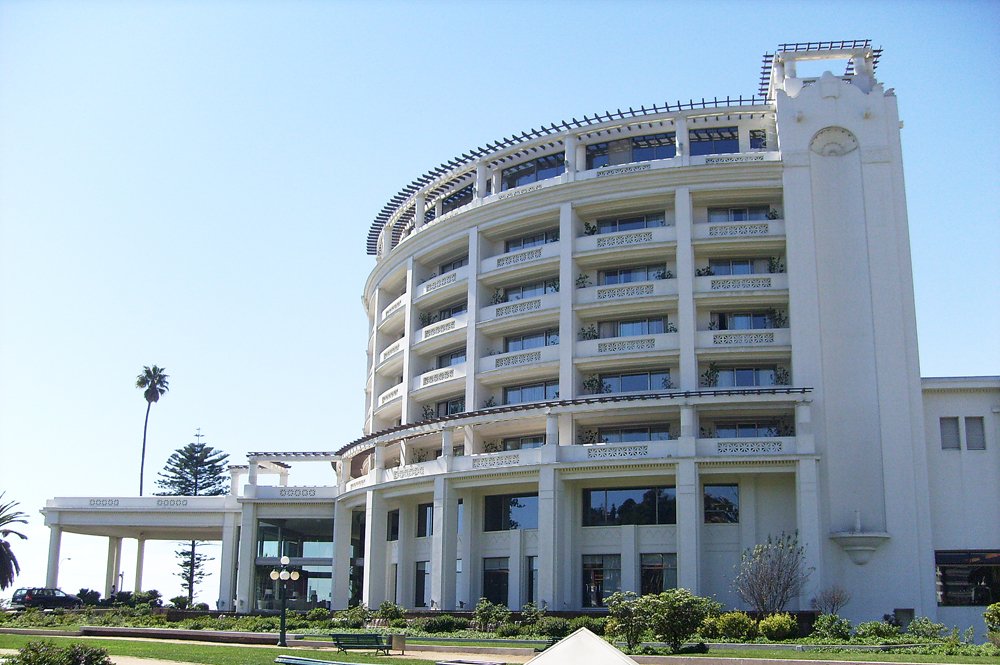 a white building with large balconies and green plants in the courtyard