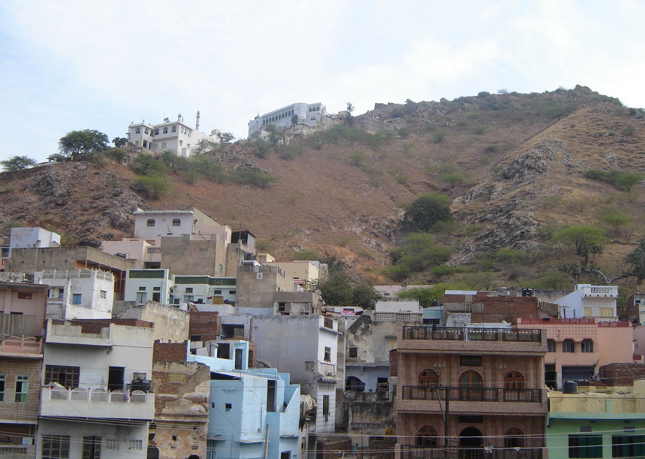 colorful buildings stand near a hill and have many windows