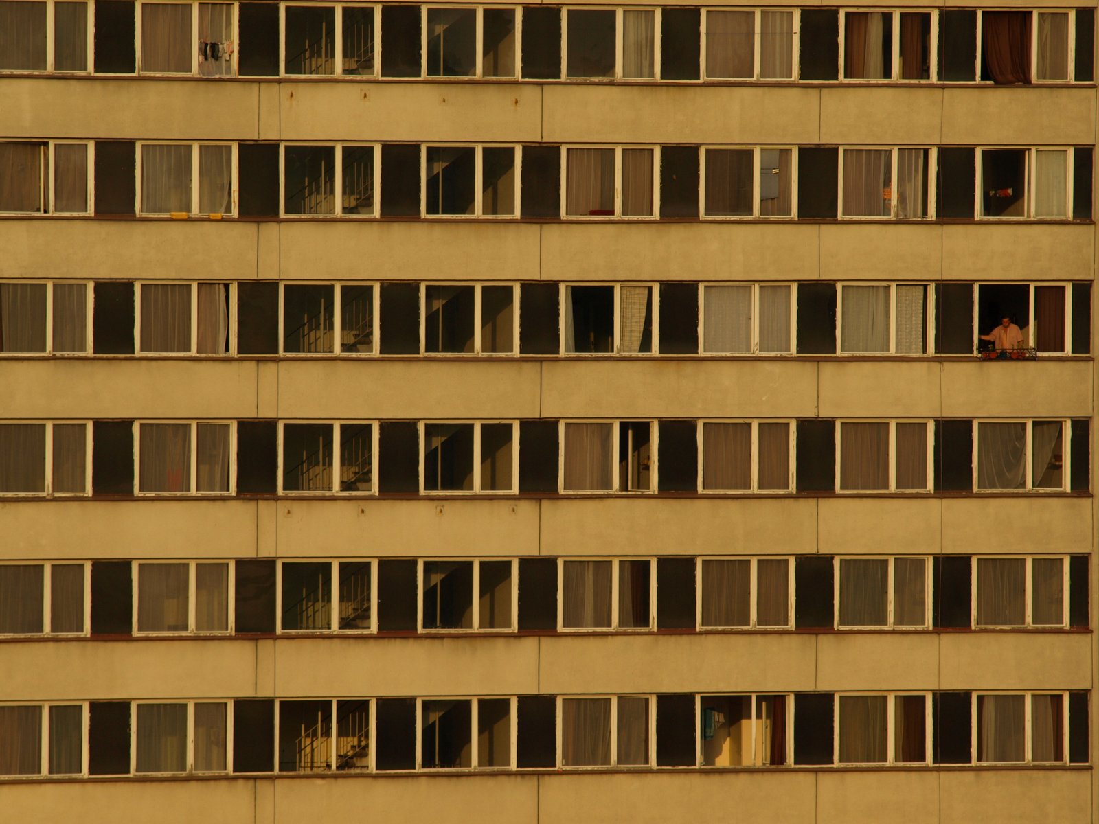 a large brown building that has several windows and is full of people