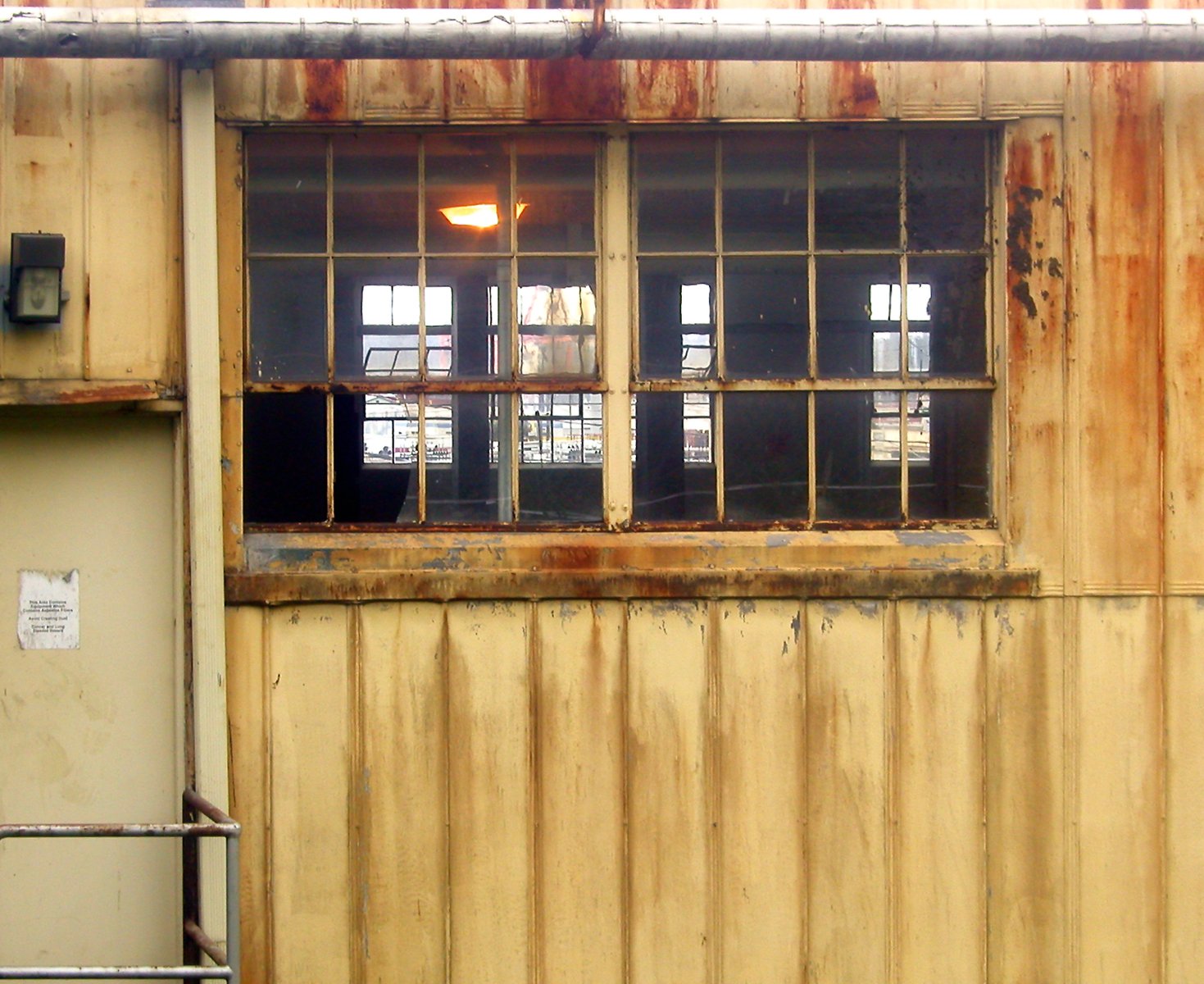 a rusty building has two windows and no curtains