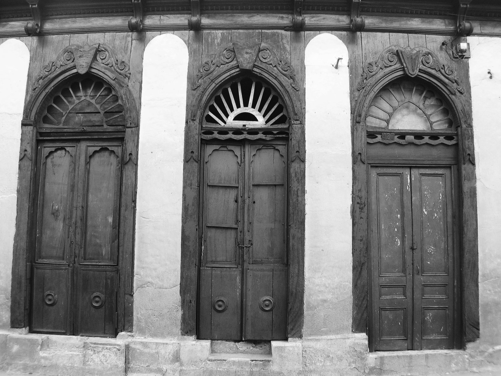 a trio of old doors sitting in front of a building