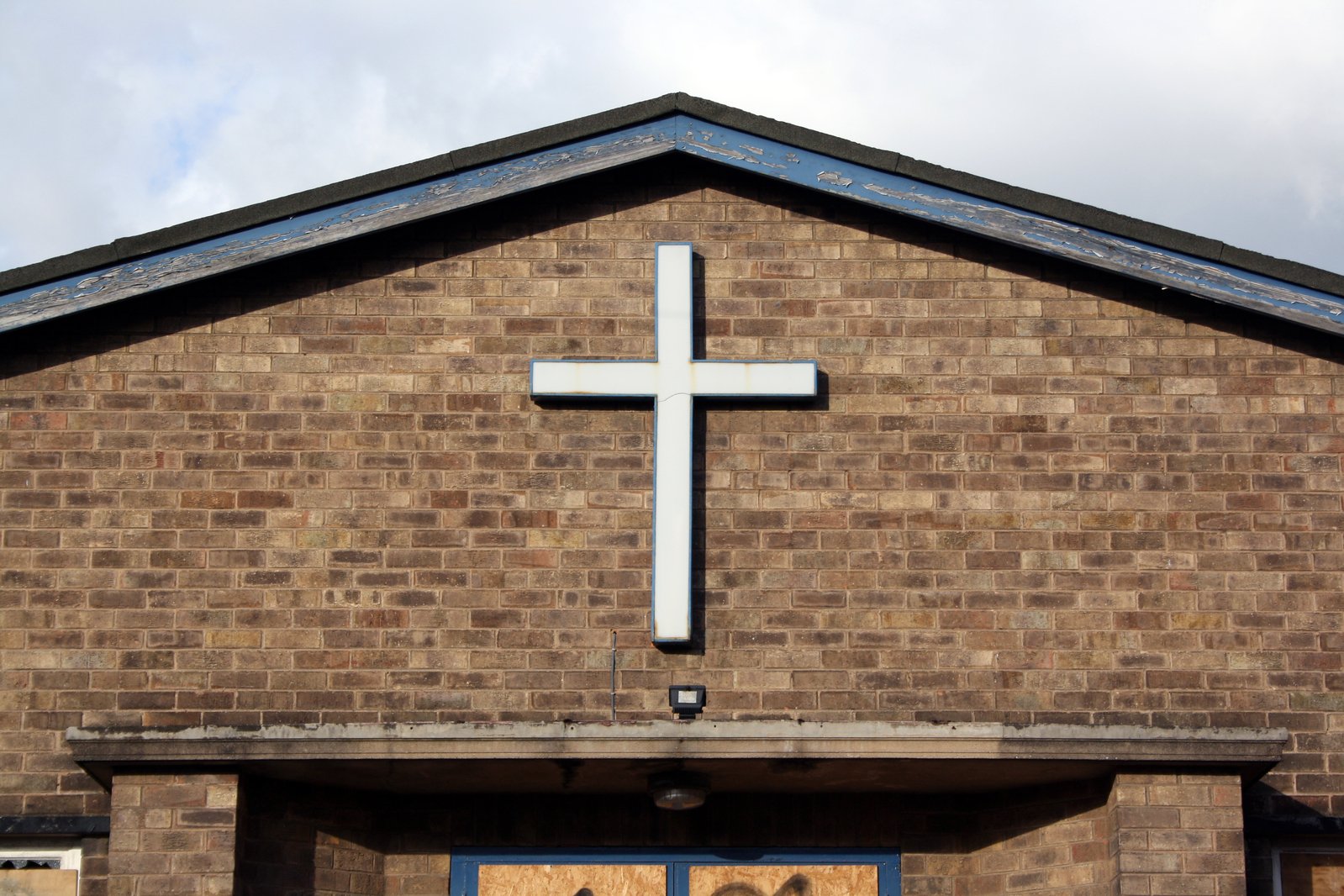 a large cross on a brick church with blue window panes