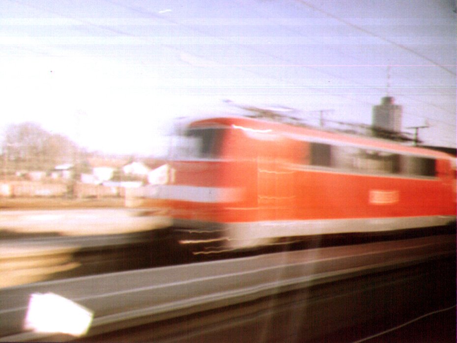 an red train speeding down the tracks past some houses