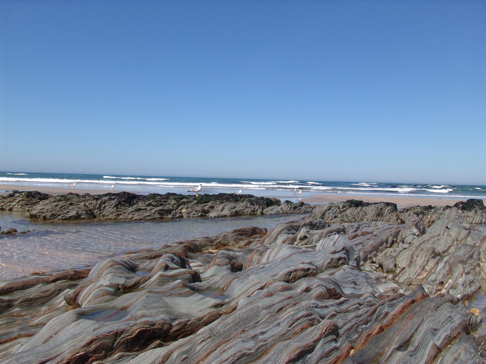 a rock is shown near the ocean with waves in the background