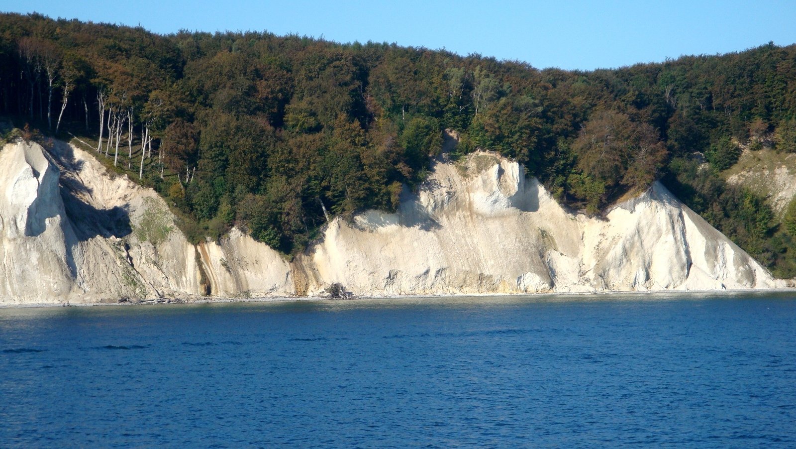 a boat on the water with some large cliffs