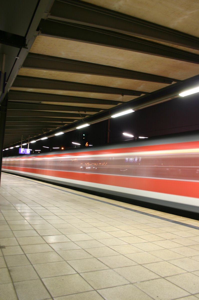 red and white subway train traveling through a station