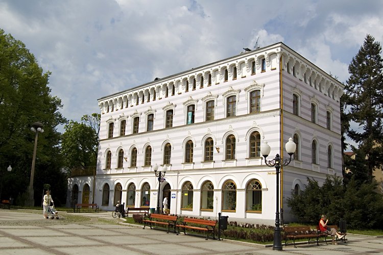 a large white building with many windows sitting next to a row of benches