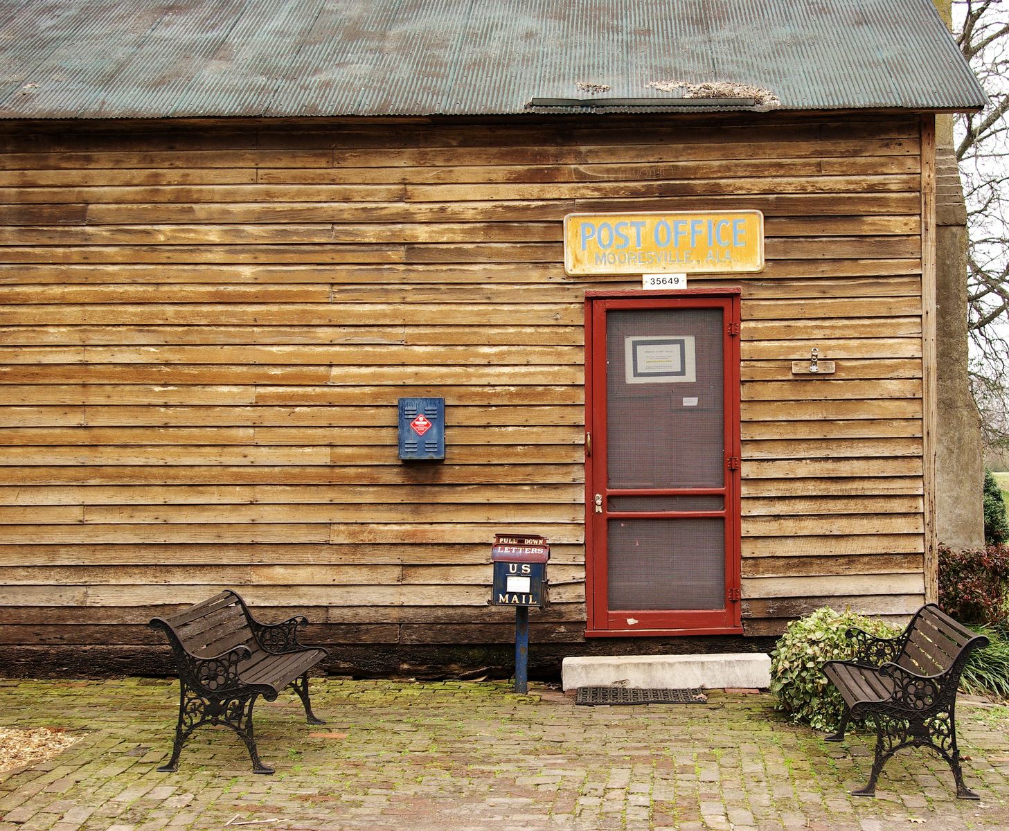 an old wooden building with a door and some chairs outside