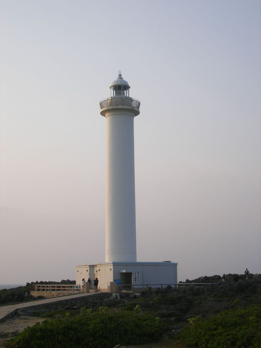 a tall white and black tower on the side of a hill