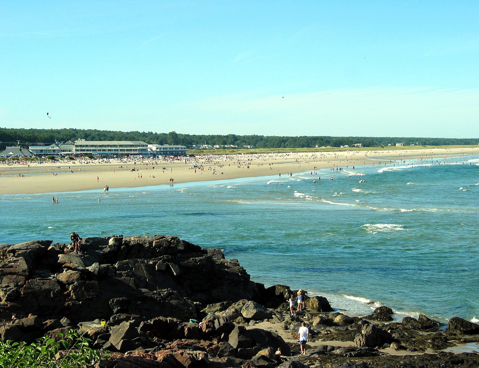 a beach with many people in the ocean and in the sand
