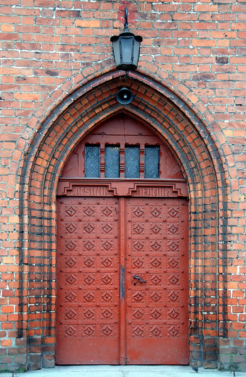 a red wooden door in an old brick building