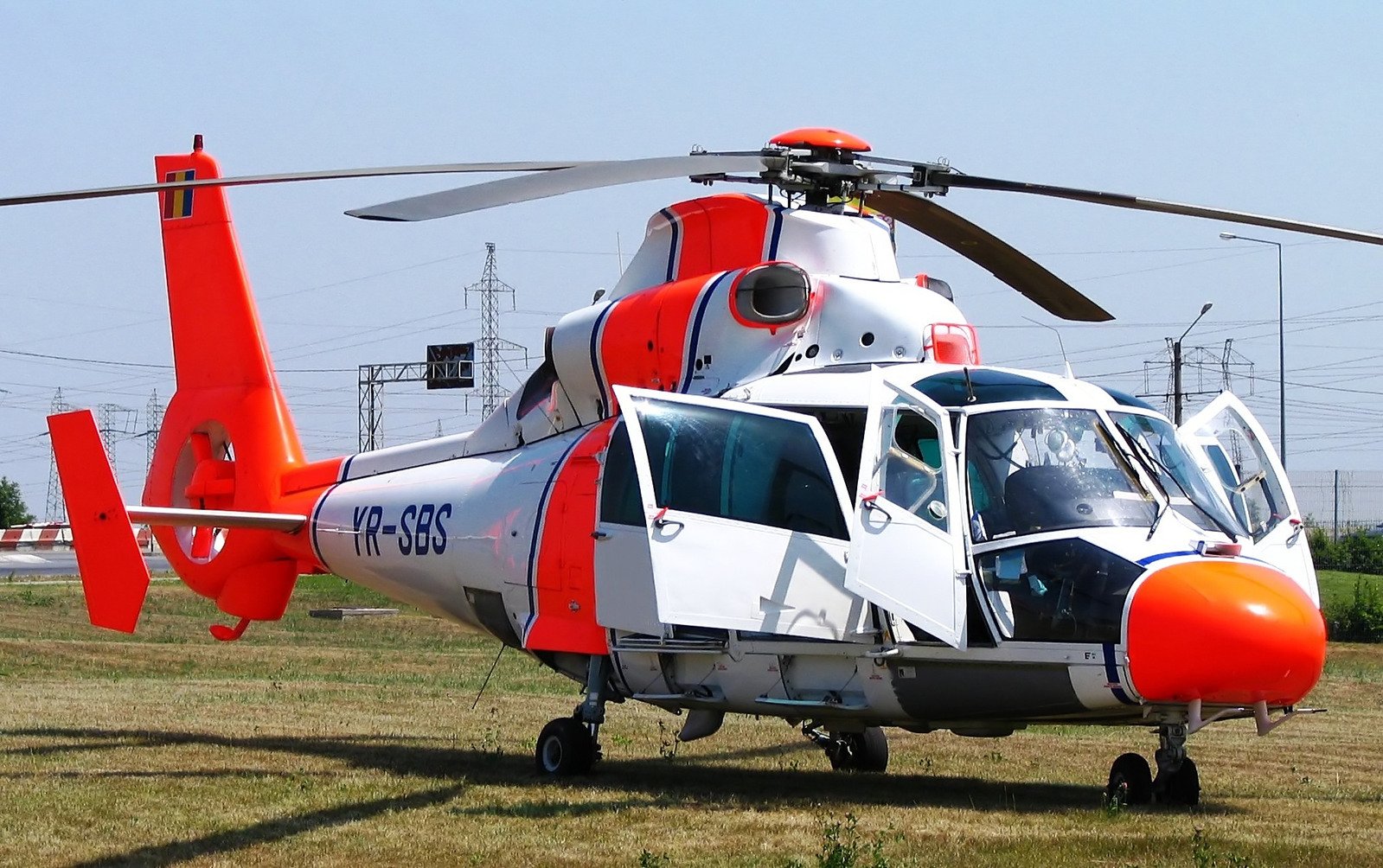 an orange and white helicopter on the grass