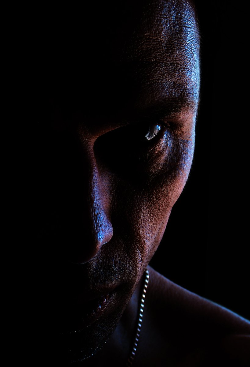 a man wearing a necklace on a dark background