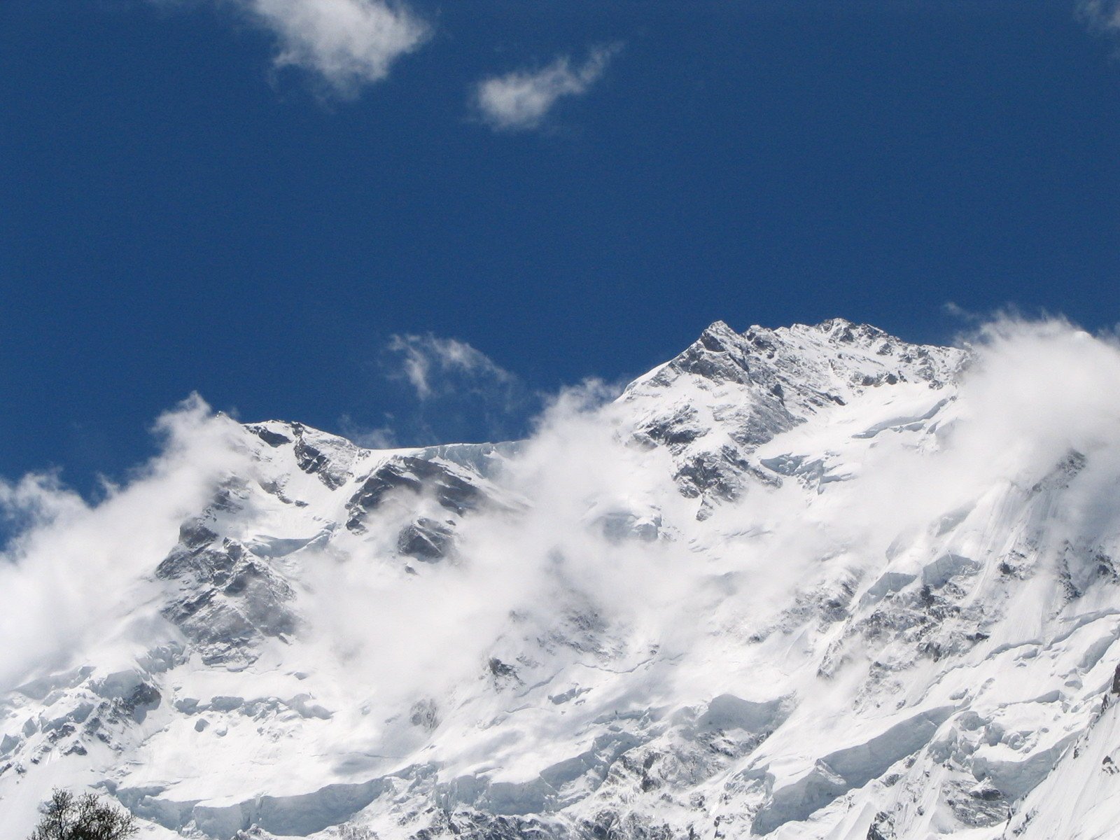 the tops of two snow covered mountains against the blue sky