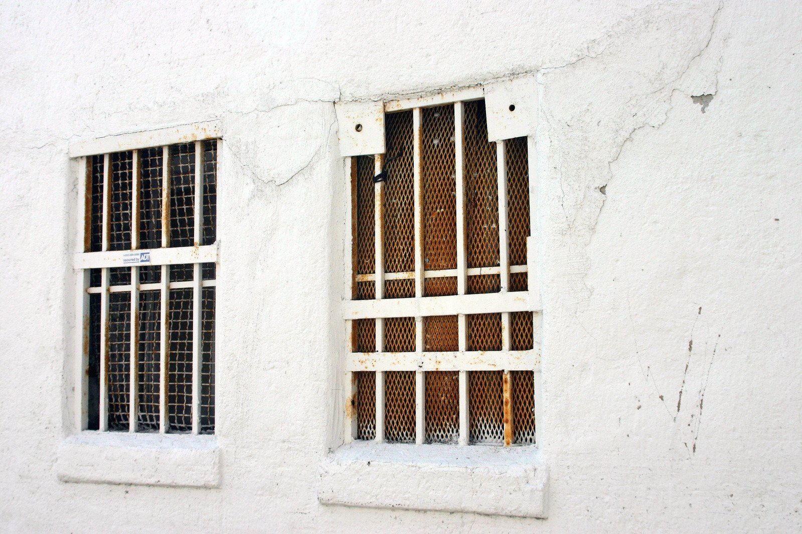 two small windows with bars are near a wall