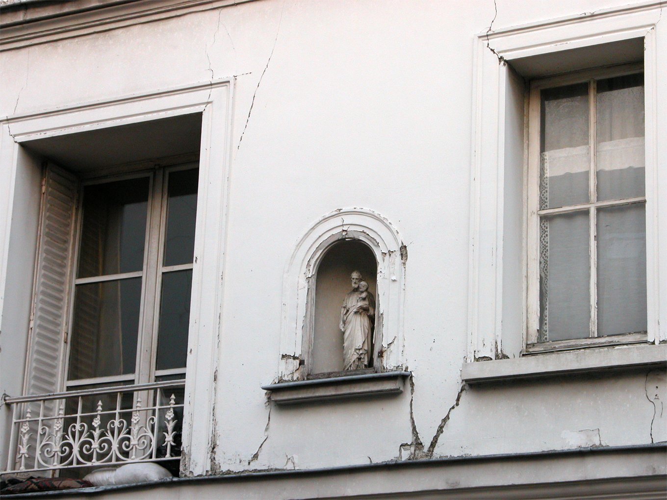 this is an old white building with the balcony broken off