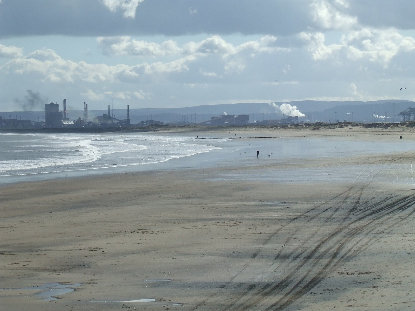 a beach with several people walking in it