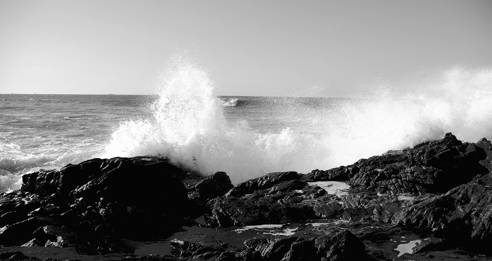 an ocean wave crashing onto the rocks with white caps