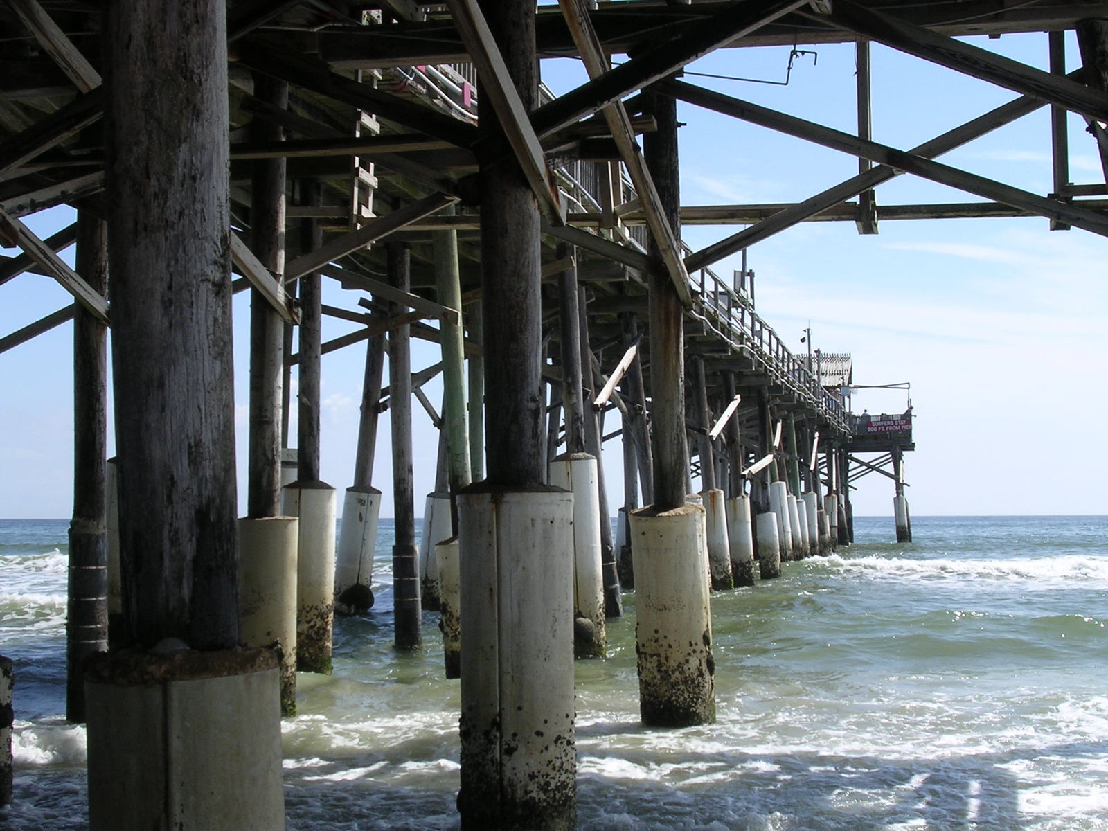 water underneath a long pier that's just about to reach shore