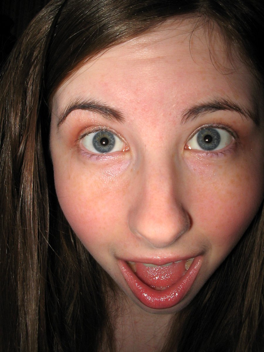 young woman's face with freckled cheeks and tongue