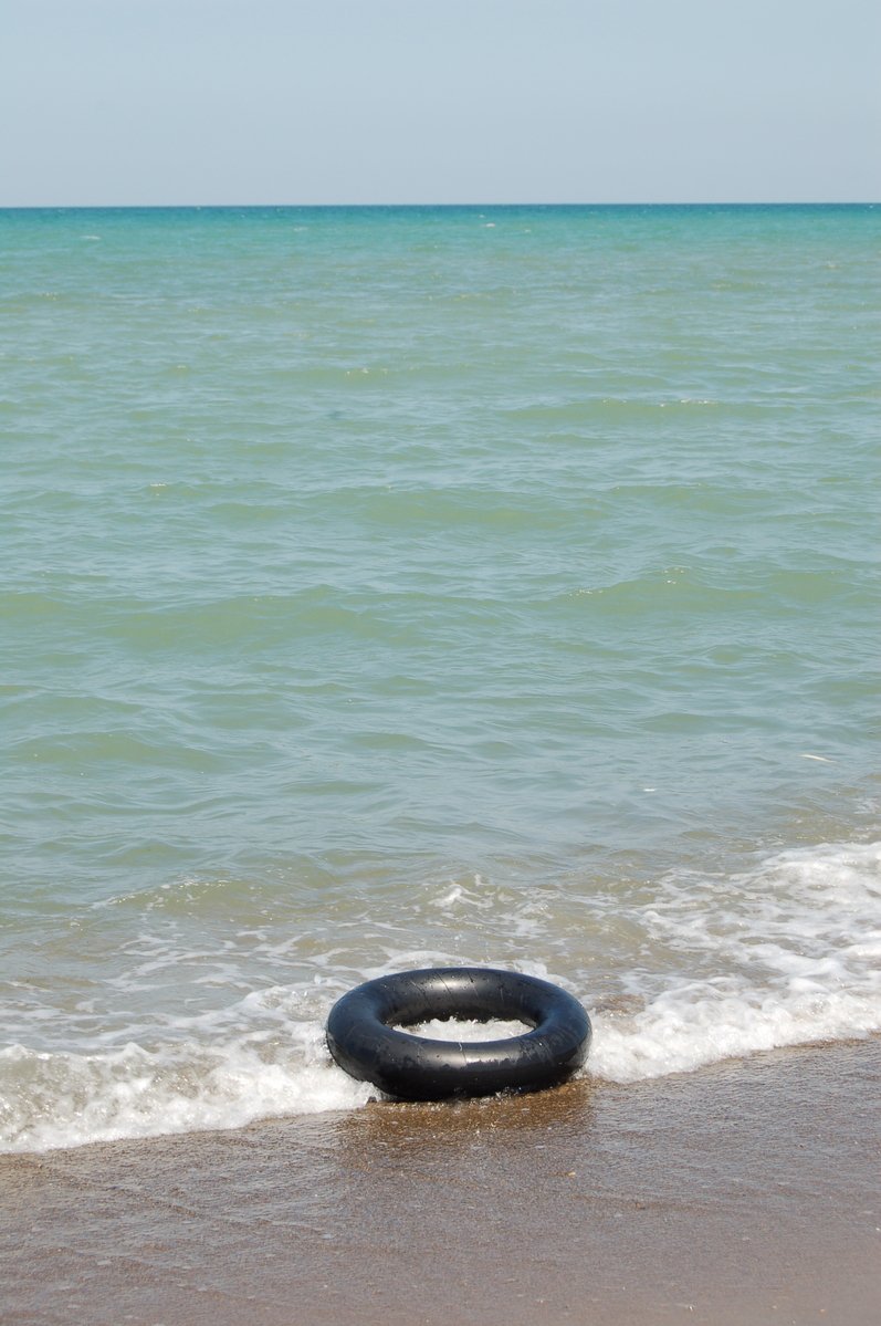 a tube floats on the beach as waves wash in the water