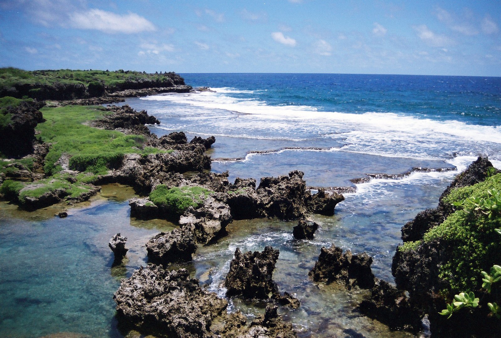 the ocean with rocks and grass on both sides