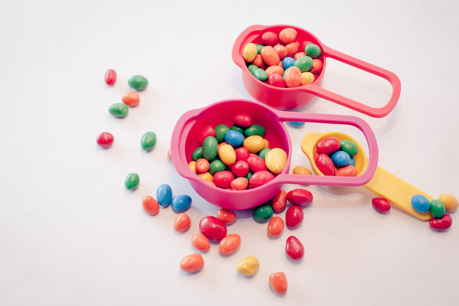 two pink bowls and scoops filled with lots of candies