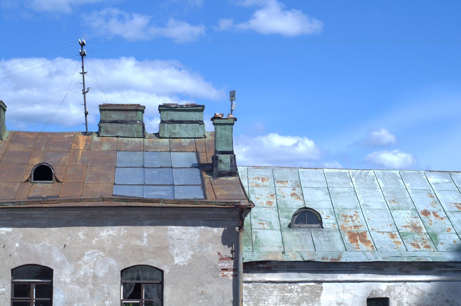 a couple of roof with two chimneys and a building with an old blue tin - tiled facade