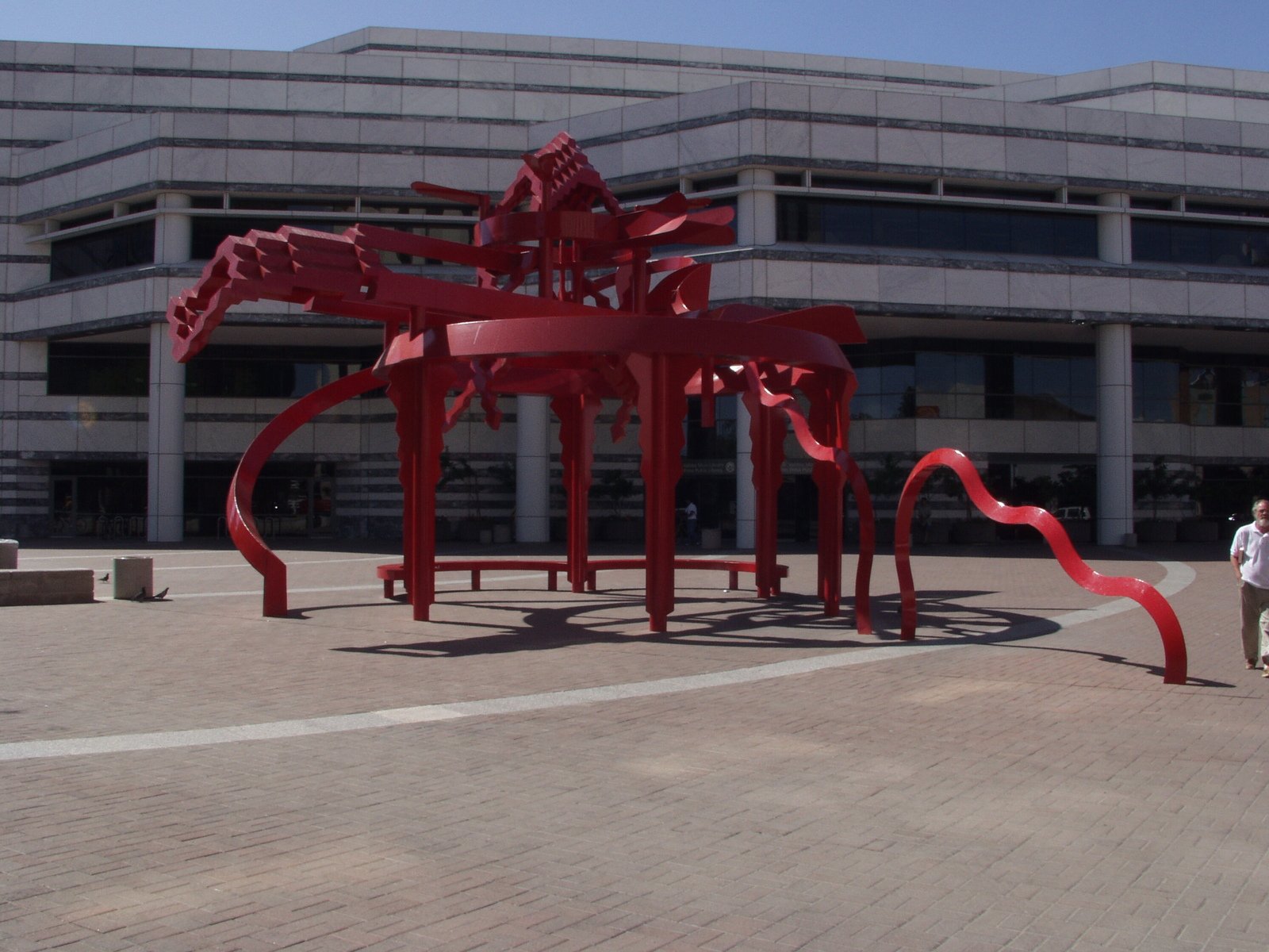 large red sculpture in plaza with building in background