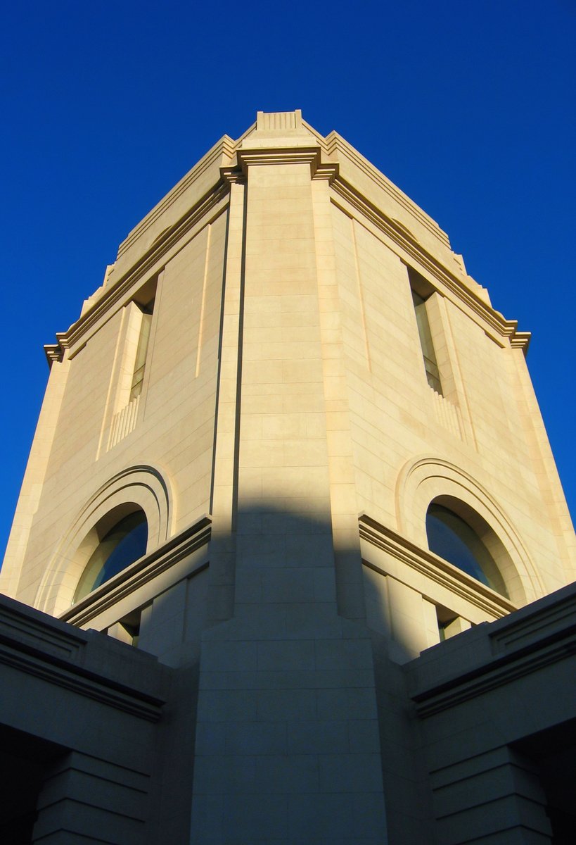 an upward view of a tall beige building with arched windows