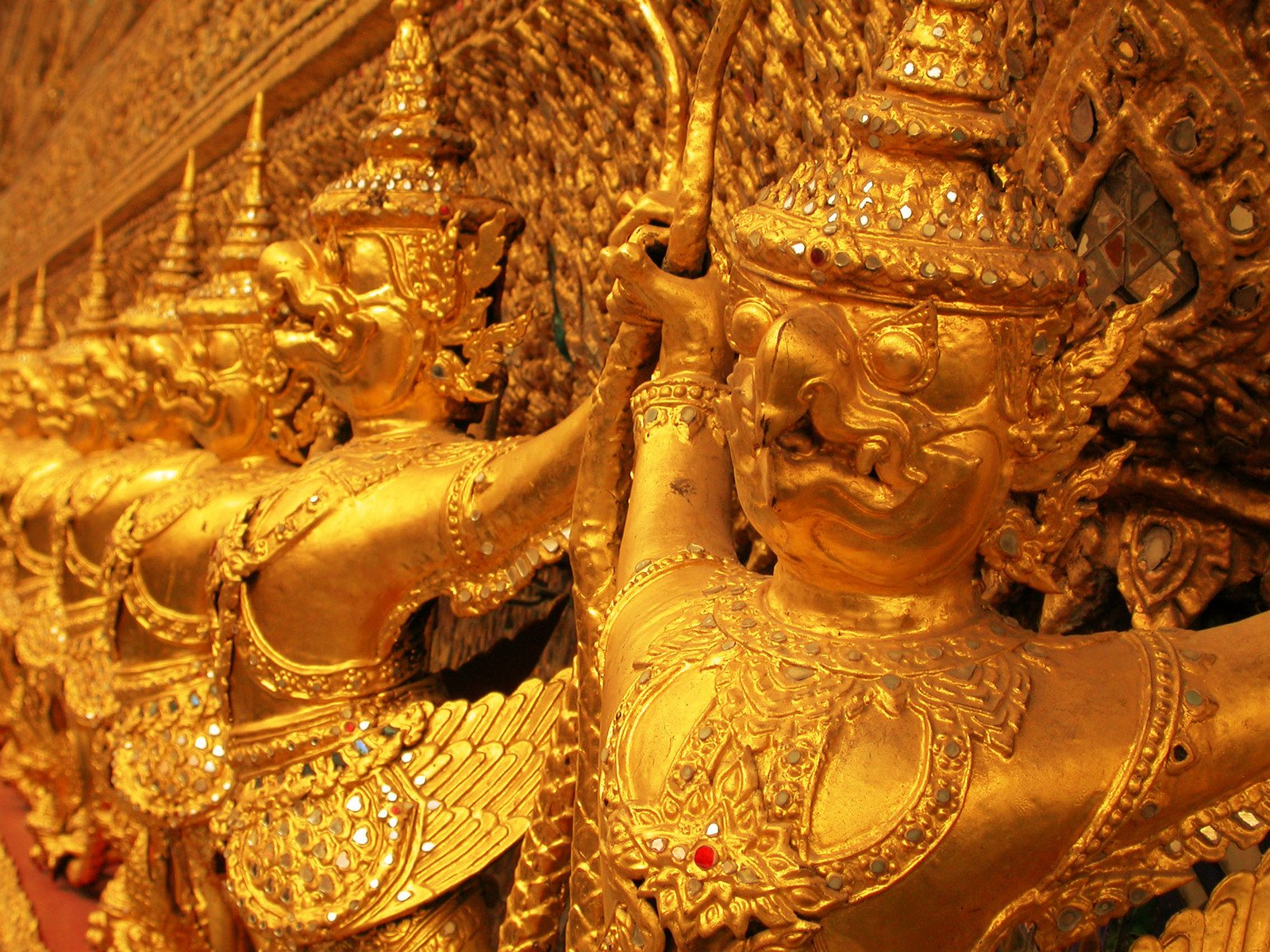 gold colored artwork of statues near a wall