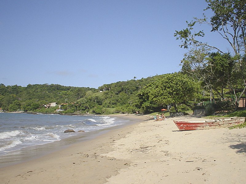 a beach with a small red boat sitting on it's shoreline