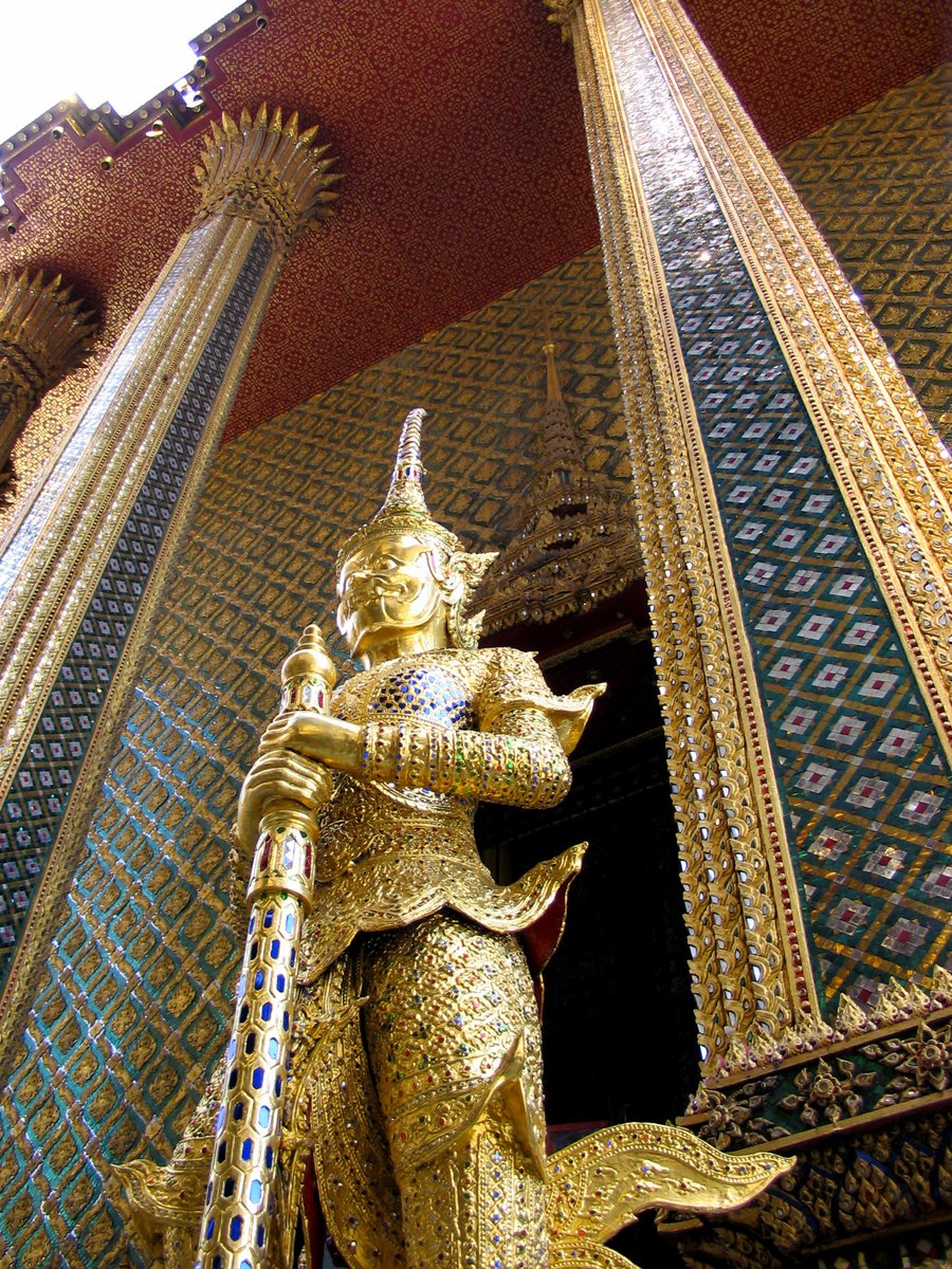 a gold statue sits beneath a tall building