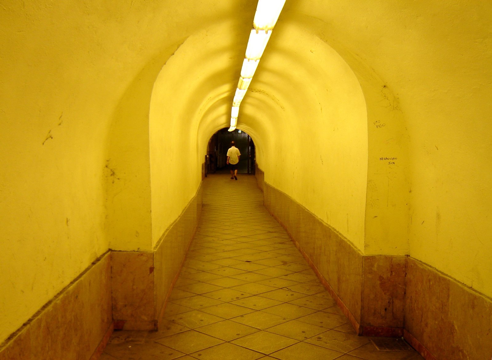 the inside of an empty yellow tunnel with tiled floors