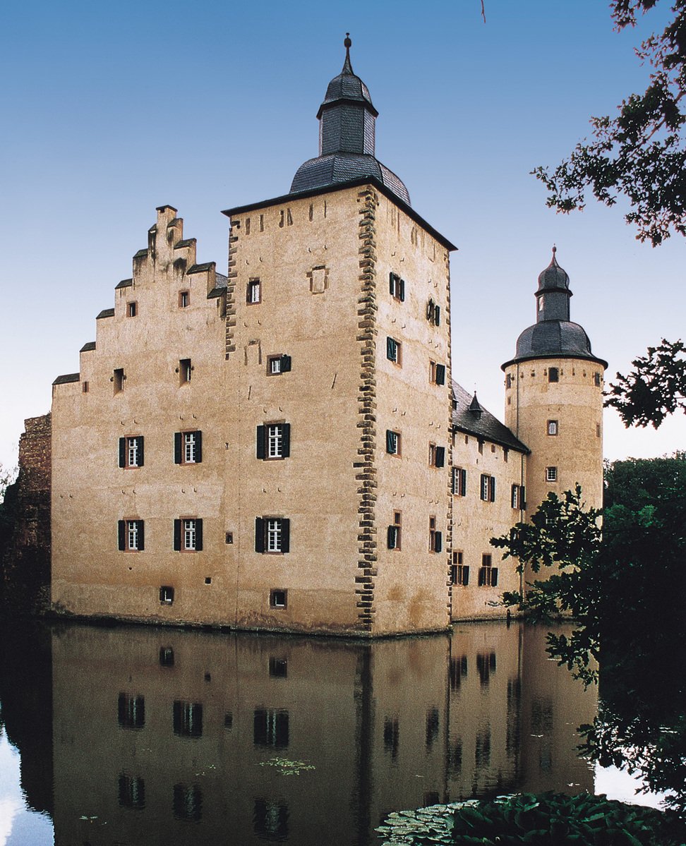 an old building with two towers that are reflecting in the water