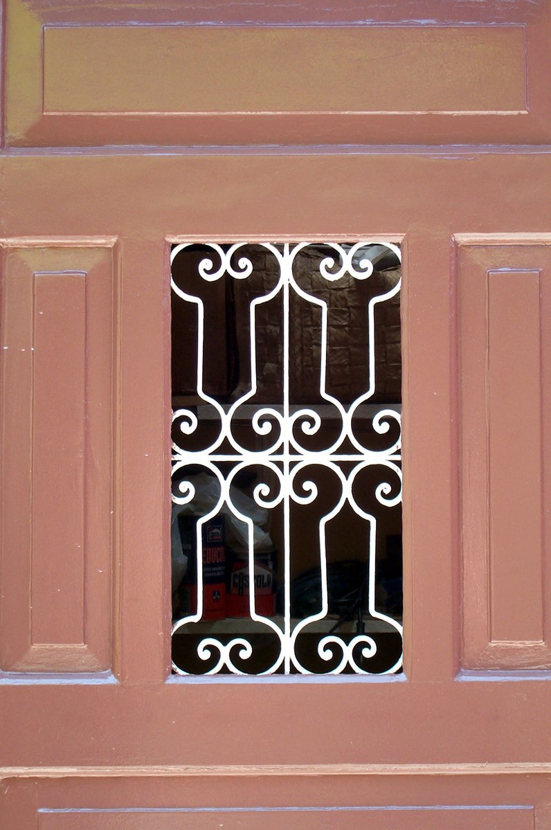 a pink door that has a window and iron bars on it