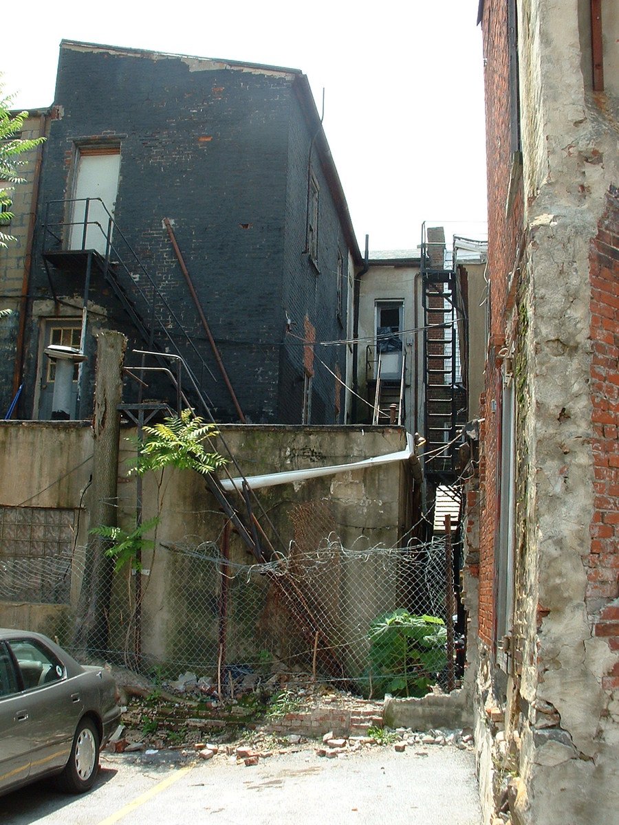 a small fire escape with a fenced in walkway between two buildings
