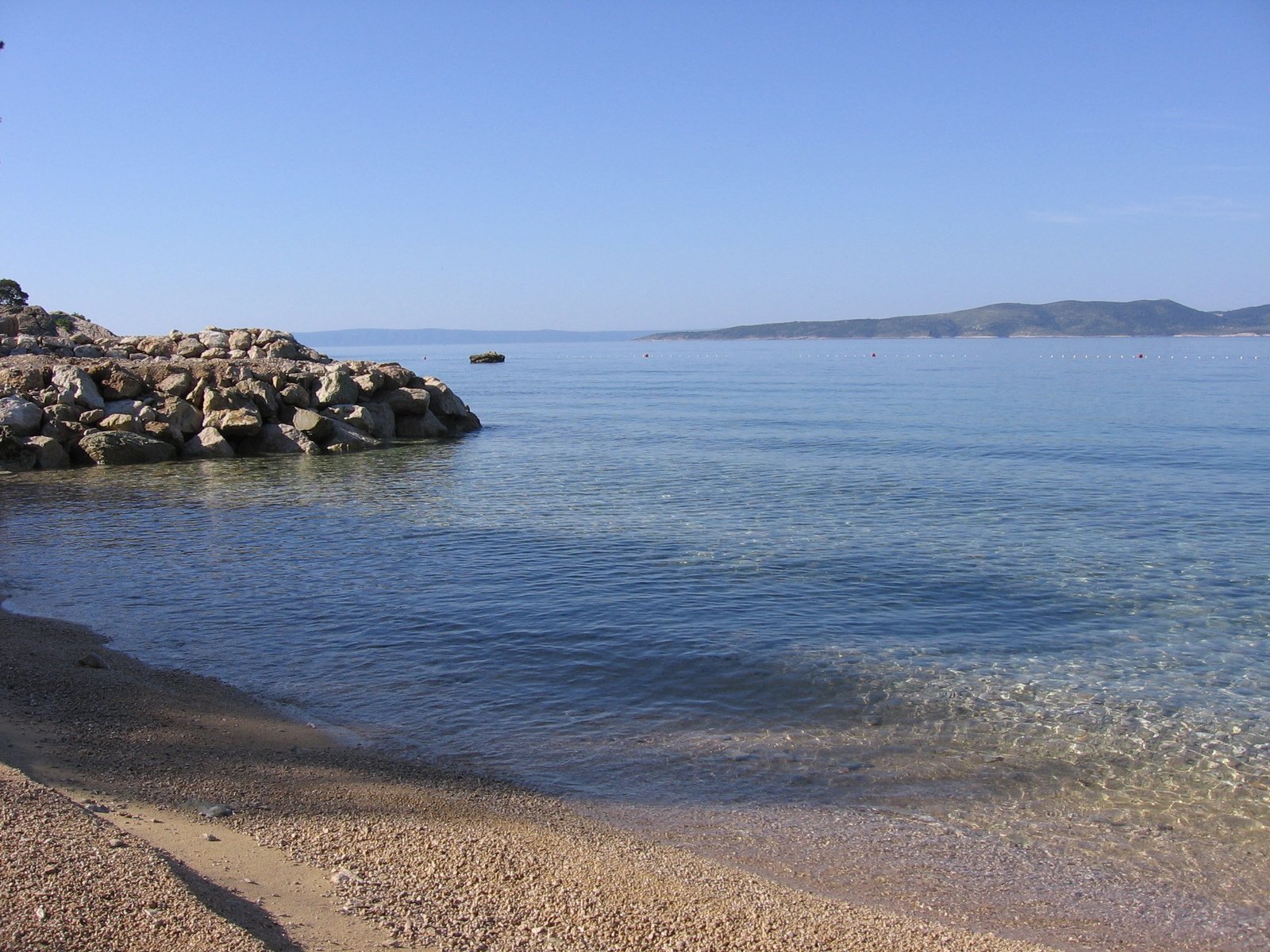 a shoreline on a sunny day with rocks in the water