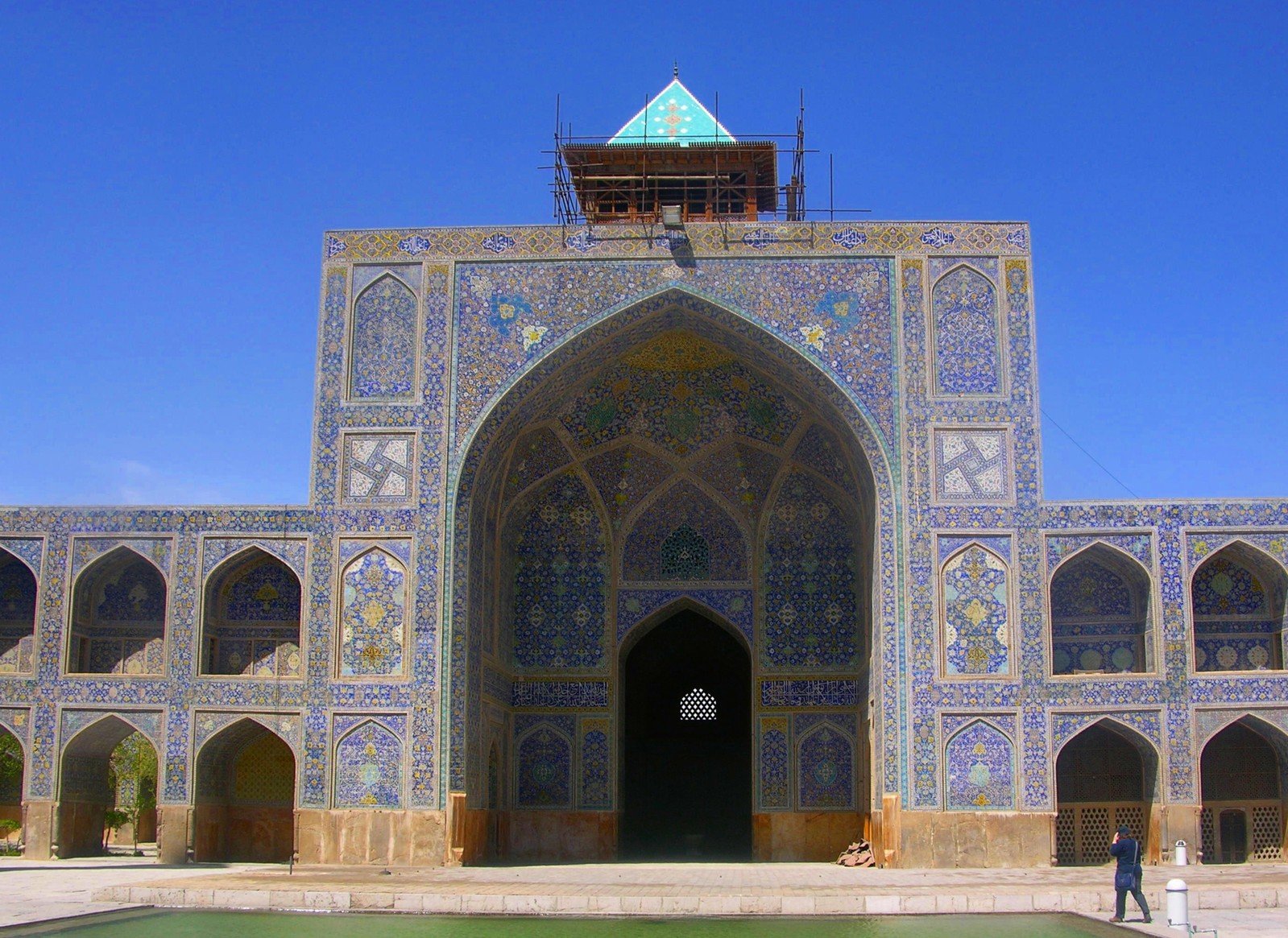 an ornate entrance to a building with green waters in front