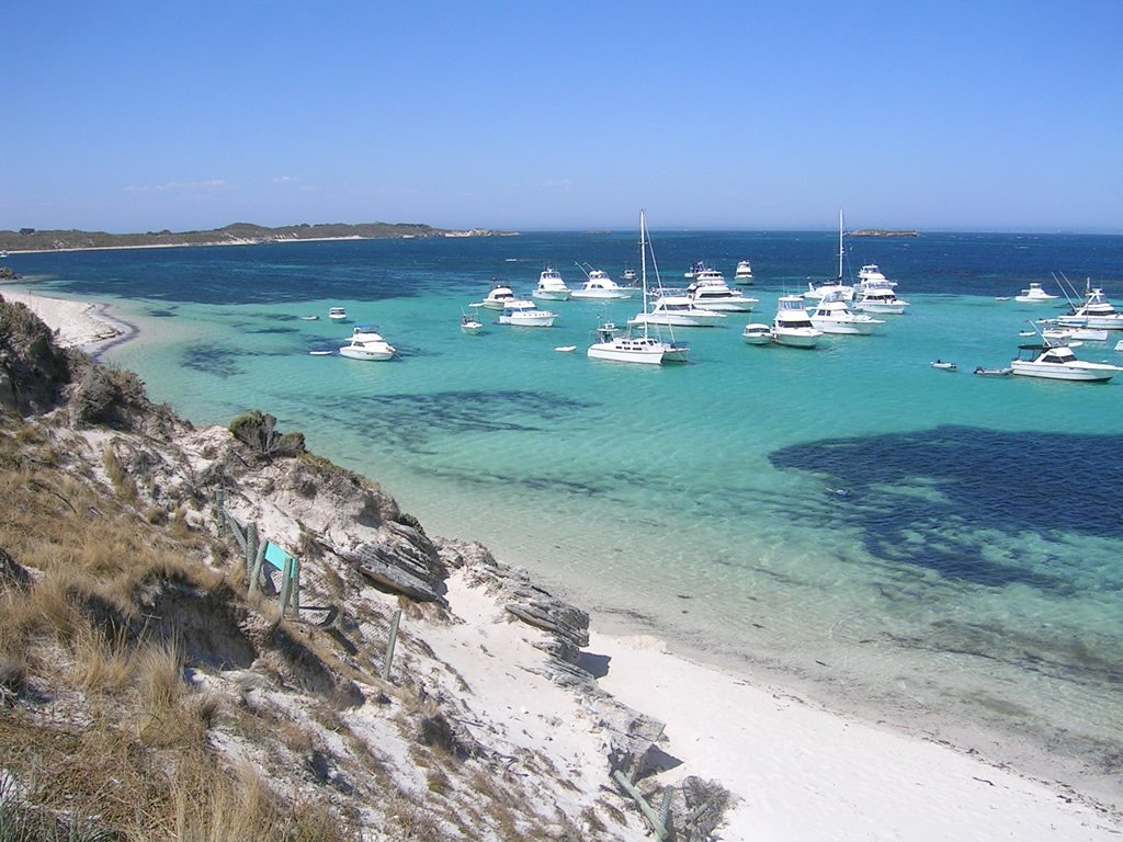 several small boats sailing in the sea on an island