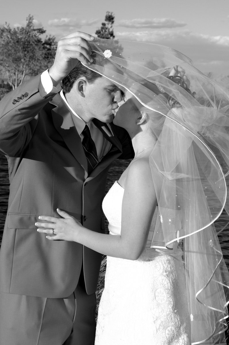 man adjusting a veil on his brides face
