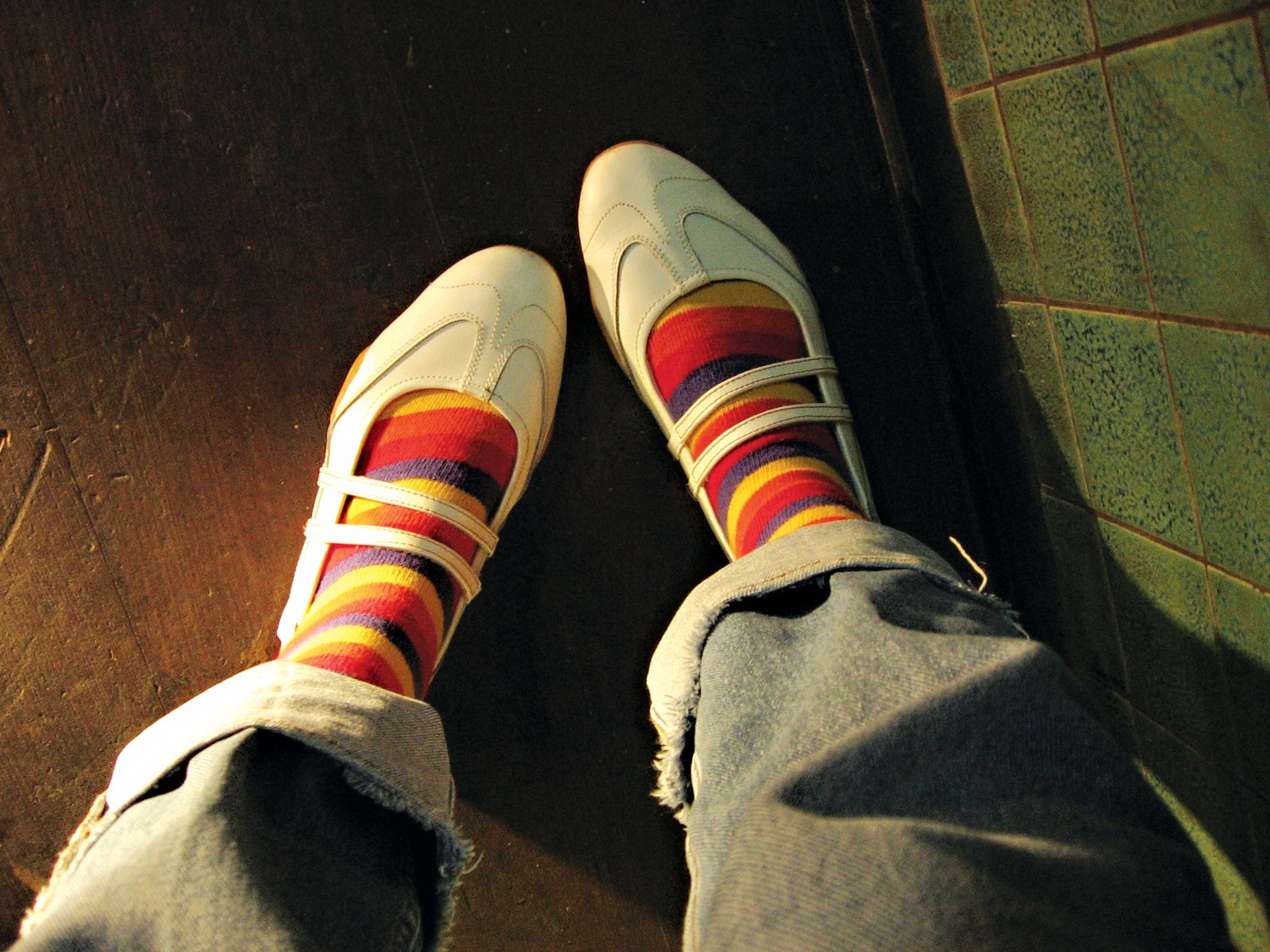 someone wearing colorful socks and a white converse sneakers