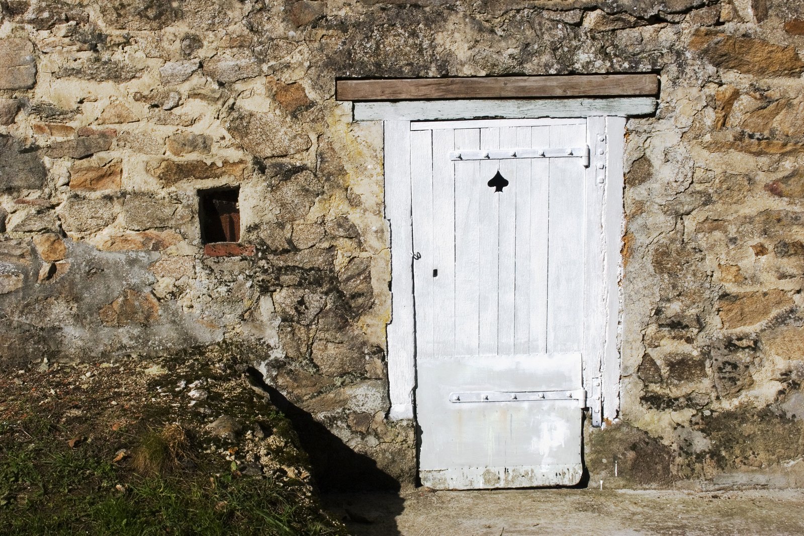 an old door and window stand in a stone wall