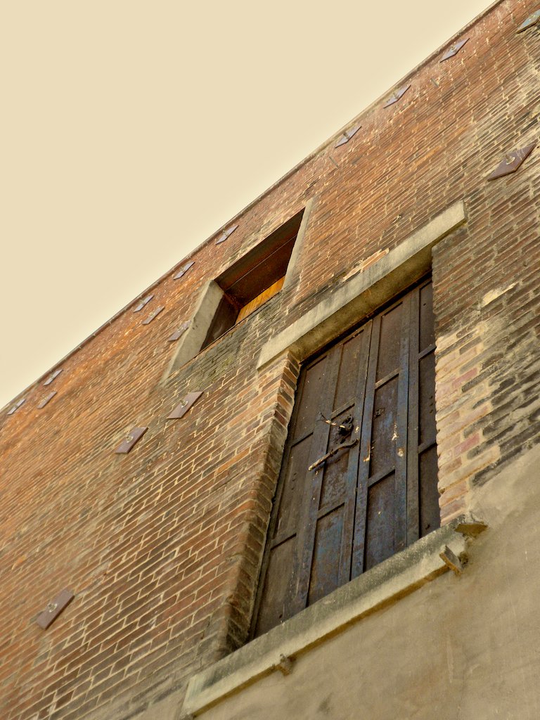 the back of an old brick building with a window on each side