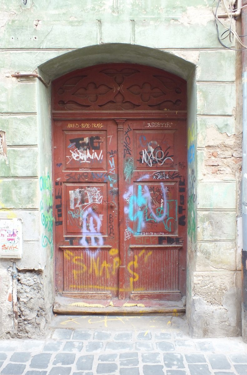 an arch with some doors covered in graffiti