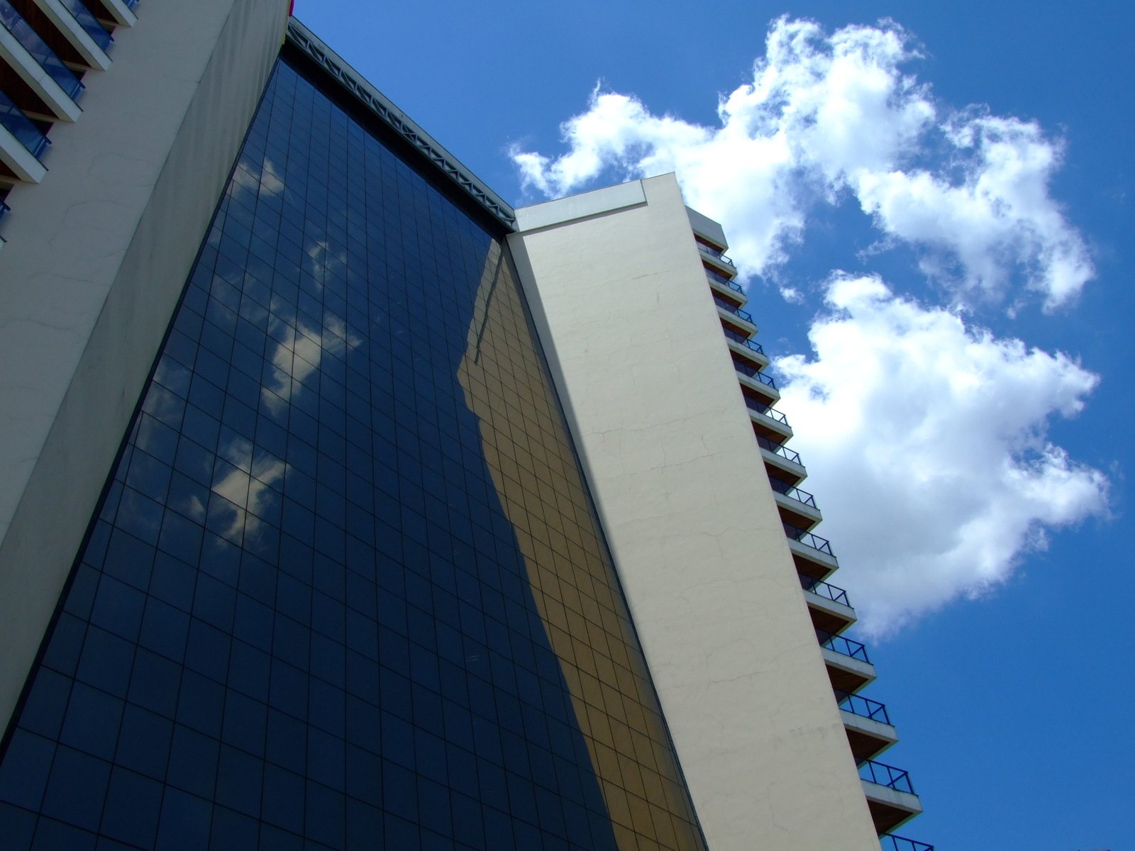 blue sky behind a high rise building and clouds reflected on it